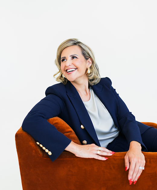 Picture of Pamela Vallero, a San Diego-based trial attorney, smiling while sitting on a couch